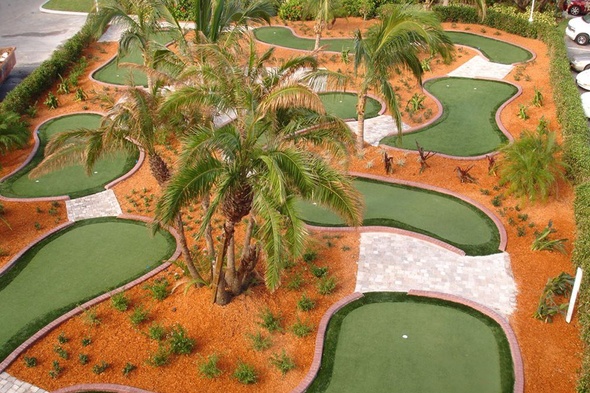 Charlotte Aerial view of a mini golf course with synthetic grass and palm trees.